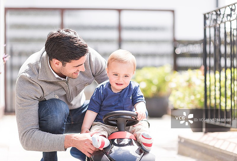 爸爸和小儿子在一起玩，儿子骑着玩具车图片素材