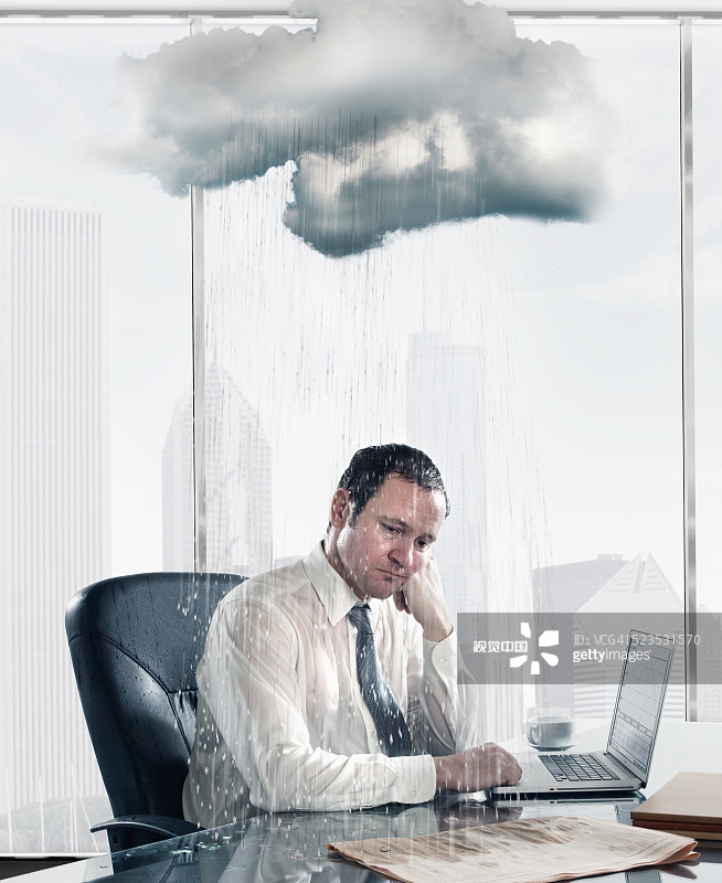 雨落在坐在辦公室辦公桌前的悲傷的商人身上圖片素材