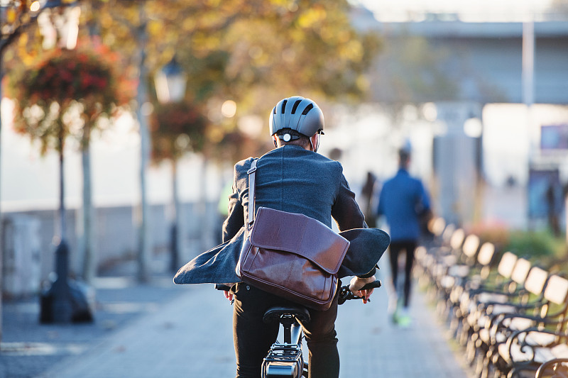 商人用電動自行車在城市上班的后視圖圖片素材