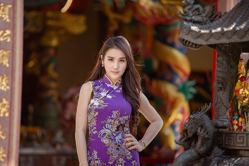中國婦女穿著傳統旗袍站在中國寺廟。圖片素材