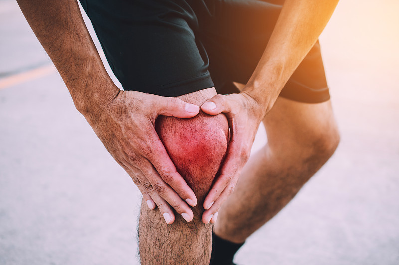 男性運動員在街上經歷膝蓋疼痛的特寫圖片素材