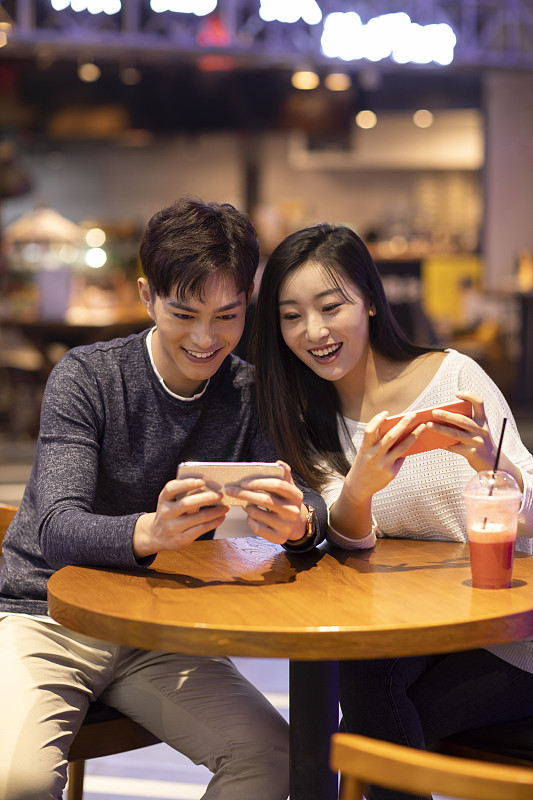 快樂的年輕情侶玩手機游戲圖片素材
