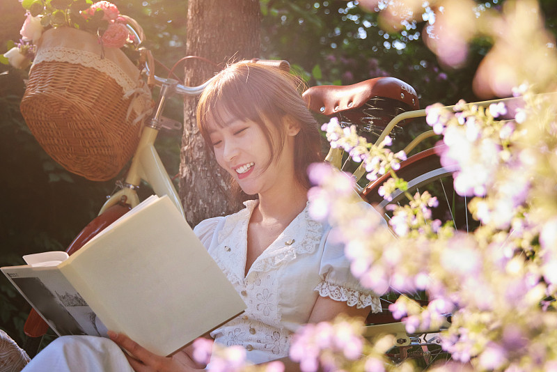 坐在花丛中看书的青年美女图片下载