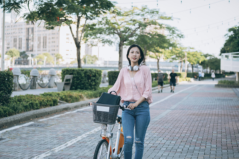 亞洲女性在市中心租用共享單車圖片素材