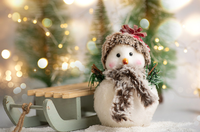 Toy snowman and winter holidays symbols and toys with shiny festive fairy lights圖片素材