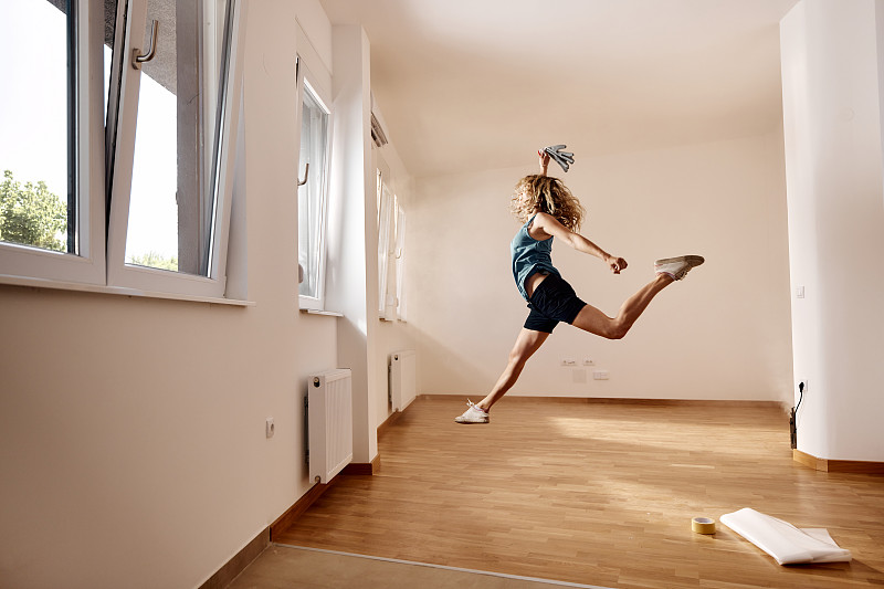 無憂無慮的女人在她的新公寓里跳躍。圖片下載