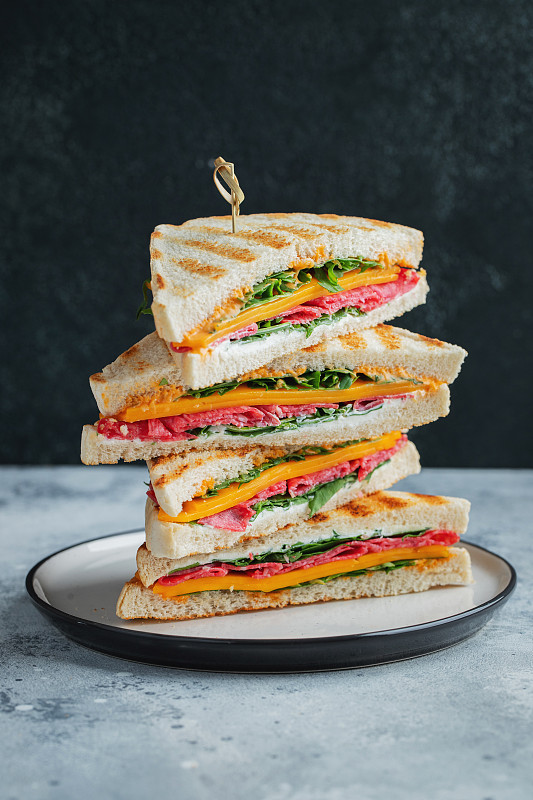 自制的大三明治，有香腸、奶酪和芝麻菜，背景是深色混凝土圖片下載