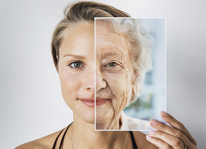 一個年輕的女人拿著一張老婦人的照片攝影圖片
