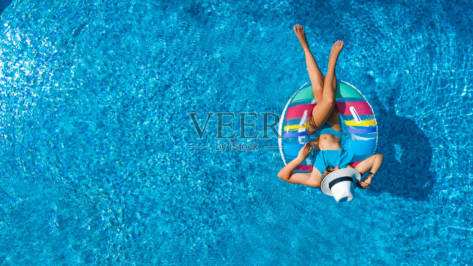 鳥瞰圖美麗的女孩在游泳池從上面，游泳在充氣圈甜甜圈和有樂趣的水在家庭度假照片攝影圖片