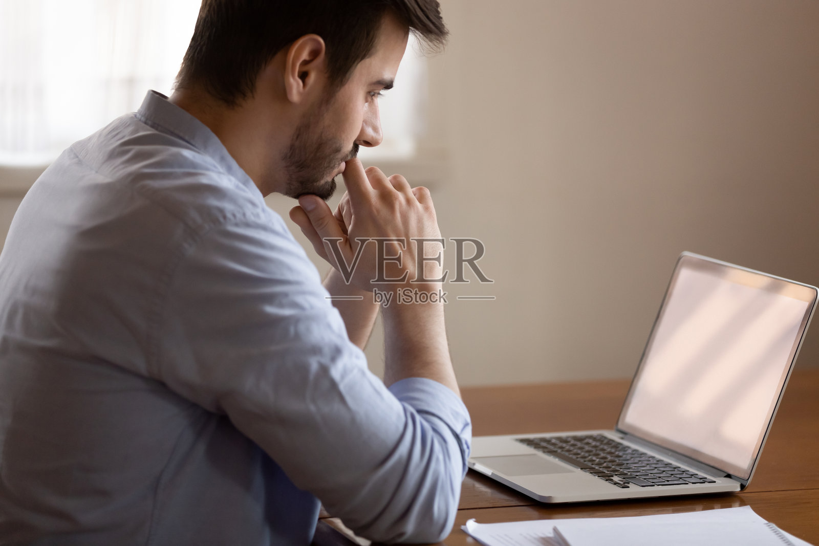 沉思的男性看着笔记本电脑屏幕，思考着做决定照片摄影图片
