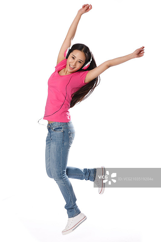 青春活力的年轻女孩听音乐跳跃图片素材