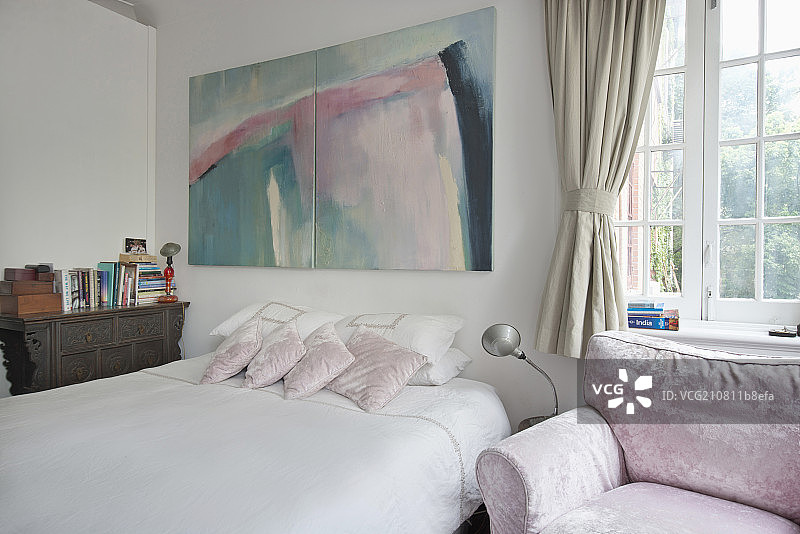 Painting over a cropped tidy bed along French window in bedroom at house图片素材