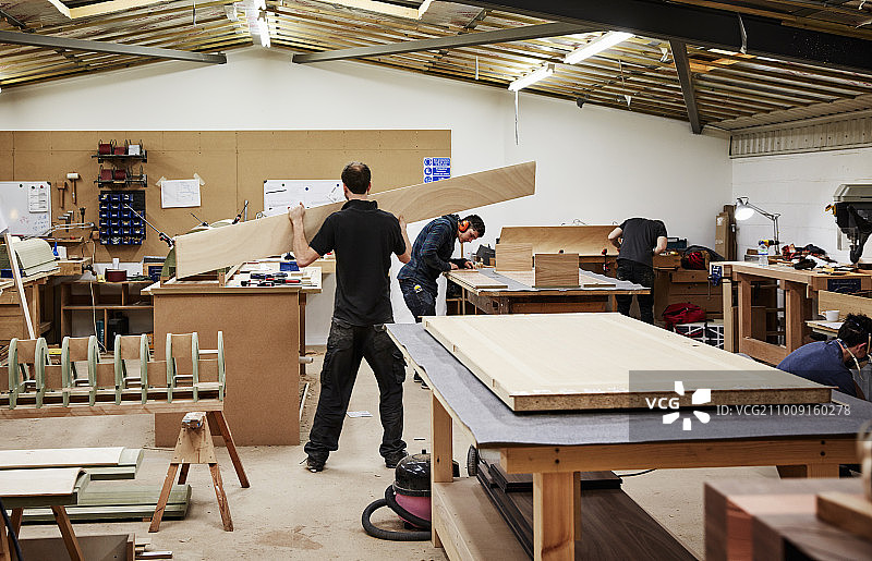一个家具作坊，使用传统技艺定制现代家具。两个人在做木材图片素材