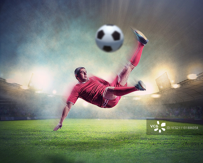 足球运动员击球。穿着红色衬衫的足球运动员在体育场里击球图片素材