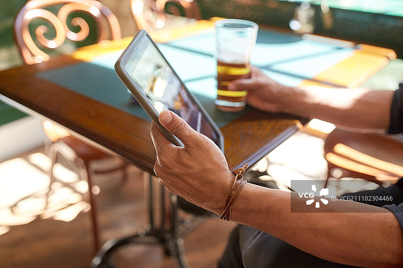 人，休闲和技术的概念-近距离的男人与平板电脑在酒吧或酒吧喝啤酒图片素材