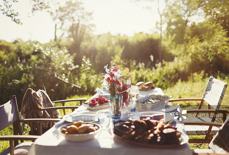 食物和花束在阳光灿烂的花园派对露台桌上图片素材