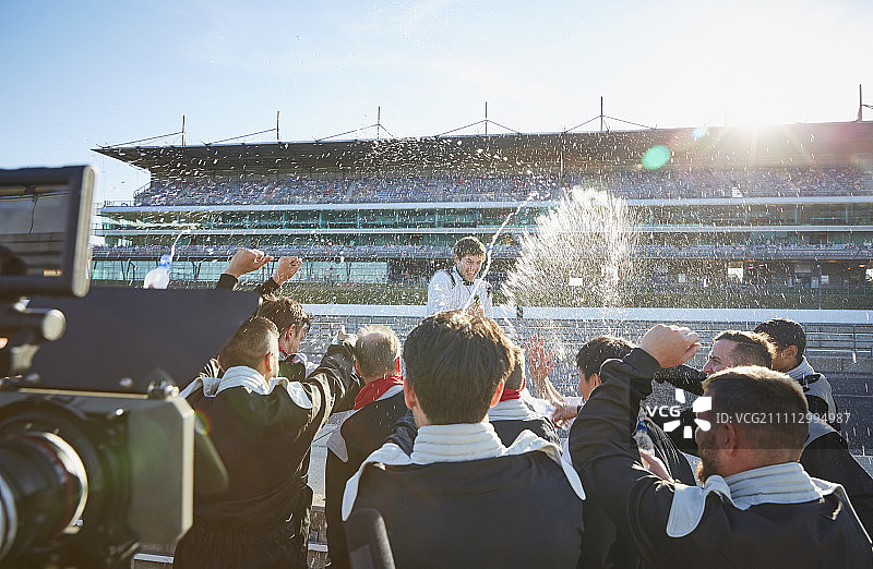 一级方程式车队在赛道上向车手喷洒香槟，庆祝胜利图片素材
