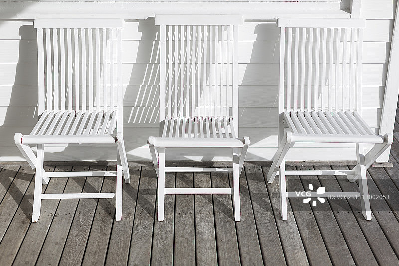 阳光明媚的院子里，白色的折叠椅排成一排图片素材