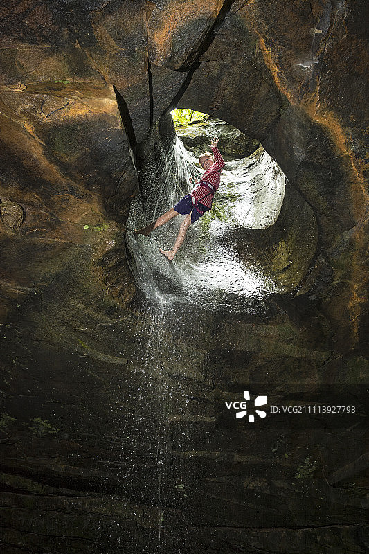 一个女人通过在阿肯色州的光荣洞瀑布的低角度攀降图片素材