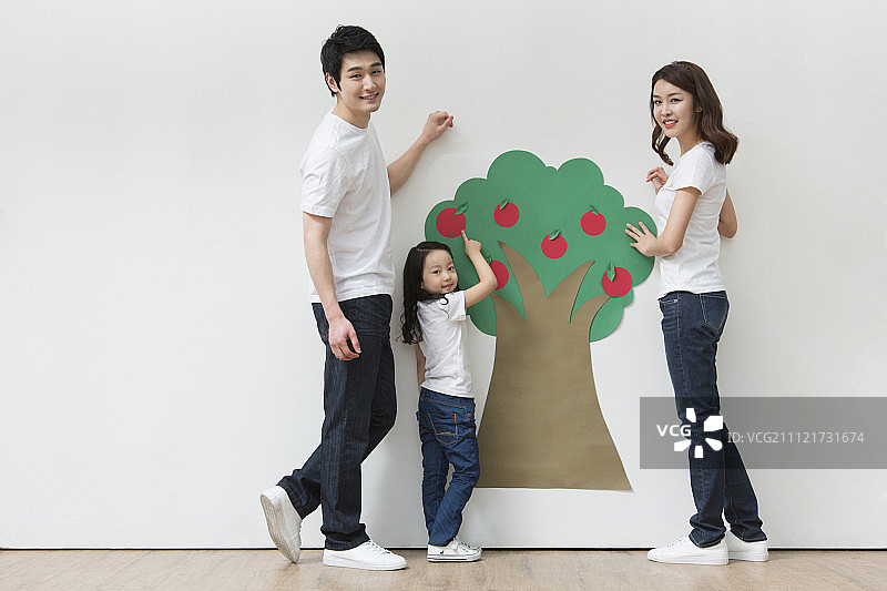 一家人站在白色的背景和苹果树图片素材