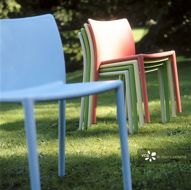 五颜六色的花园椅子叠放在草坪上，还有蓝色的花园椅子图片素材