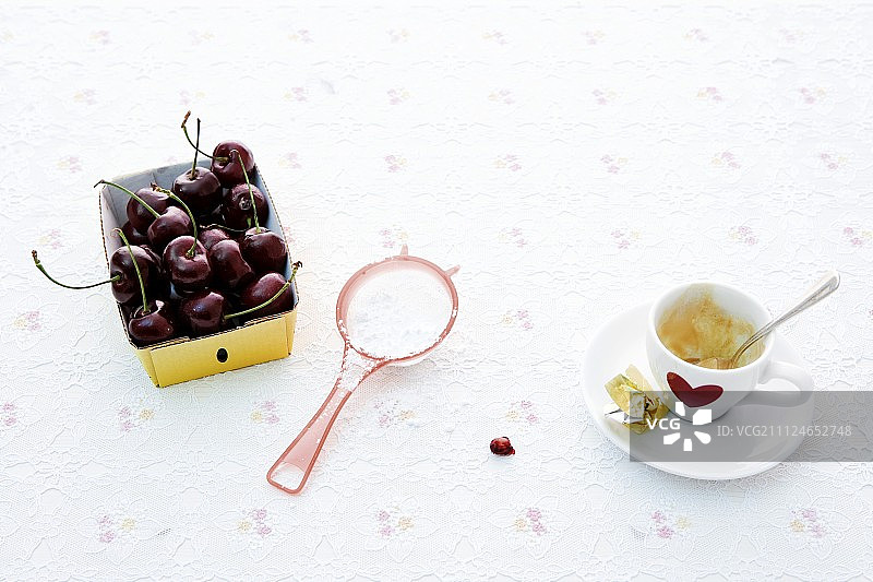 硬纸盒里的樱桃，筛子和咖啡杯，白色背景图片素材