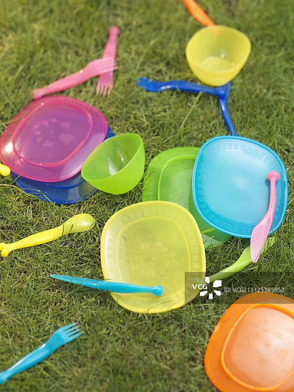野餐塑料，盘子，刀叉在草地上图片素材