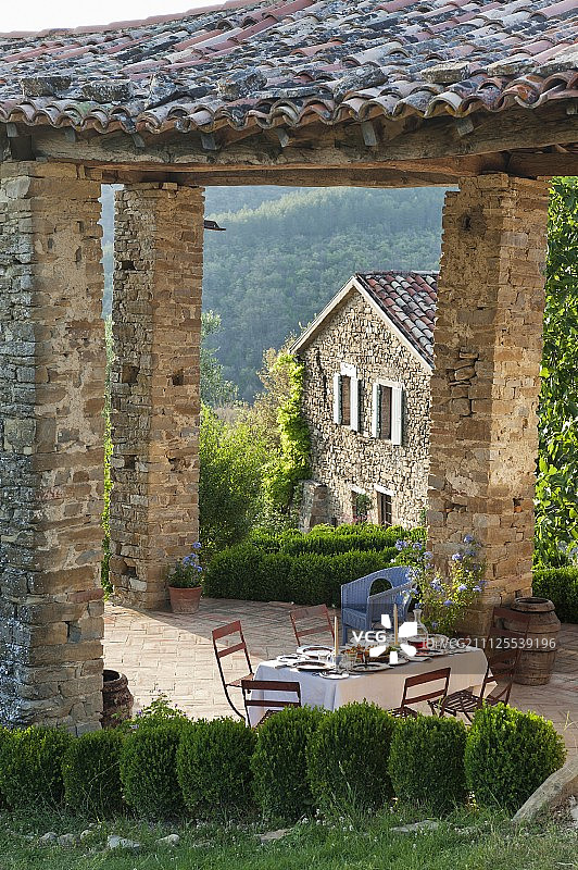在意大利风景的夏季，在乡村瓷砖屋顶的露台下设置餐桌图片素材