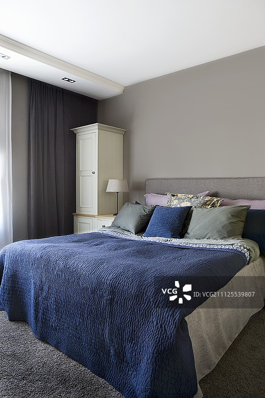 卧室里铺着蓝色床罩的双人床漆成浅灰色图片素材
