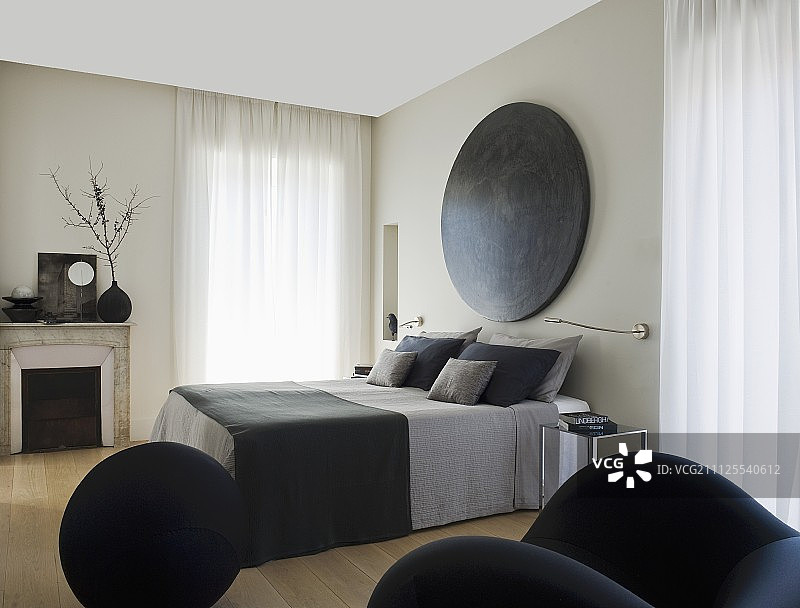 在优雅的卧室里，法式床，下面是灰色床单，墙上挂着圆形艺术品图片素材