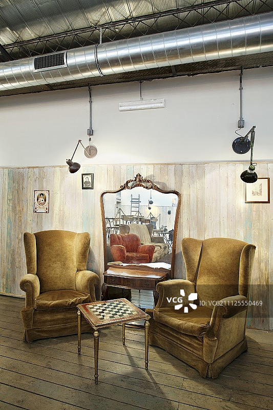 舒适的座位区与棋盘桌和毛绒阅读椅前的大镜子倚在墙上图片素材