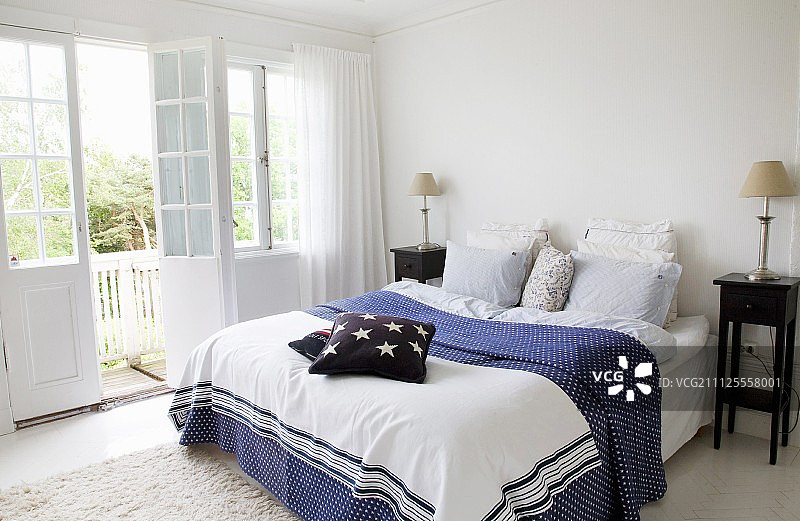 卧室双人床配有蓝白图案的床罩和深色木质床头柜图片素材