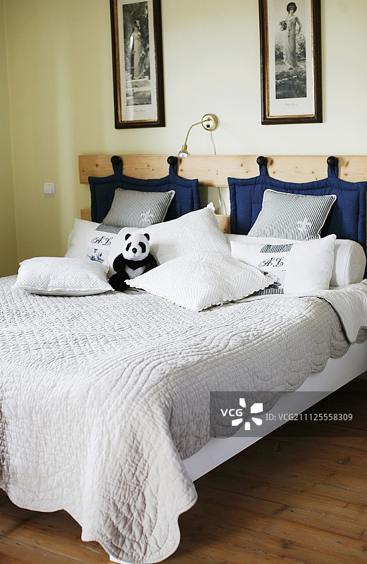 双人床，被子和蓝色绗缝垫挂在木制床头板的挂钩上图片素材