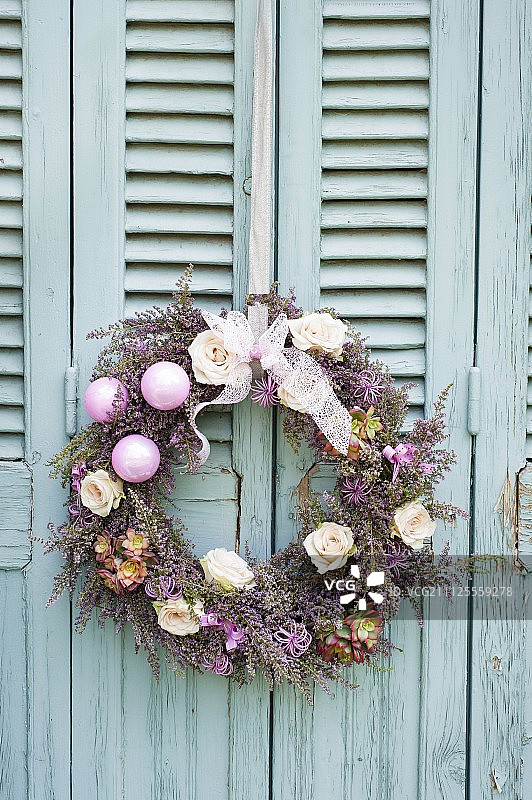 绿松石木门上挂着装饰着鲜花和小饰物的花环图片素材
