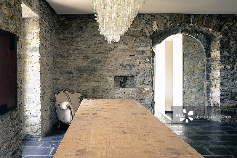 在利古里亚农舍里，长桌子上方的吊灯和巴洛克式扶手椅靠在质朴的石墙上图片素材