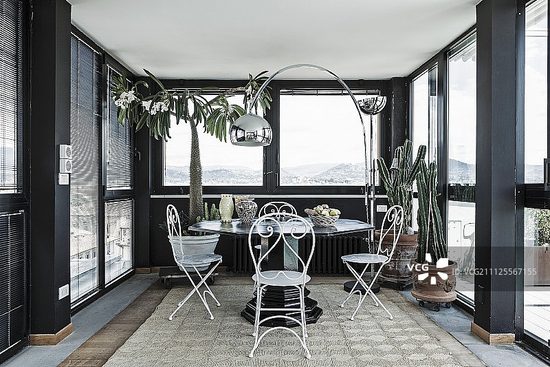 座位区与精致，白色金属椅子和弧灯在黑色温室顶楼公寓图片素材