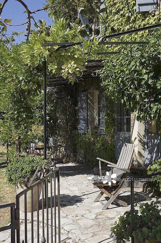 在Provençal带淡蓝色百叶窗的客房外，小石头铺的露台和爬高的铁凉棚图片素材