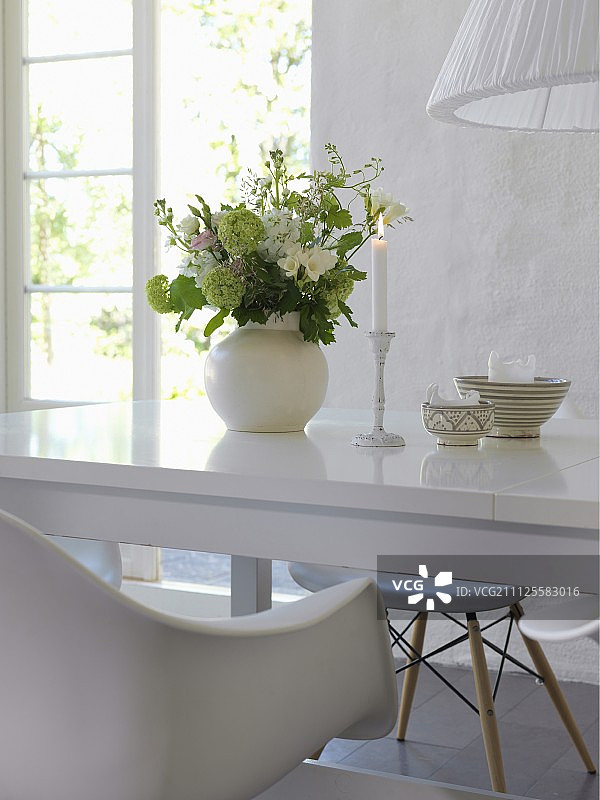 在敞开的露台门前，闪亮的白色桌上摆放着浪漫的点燃的蜡烛和花瓶图片素材