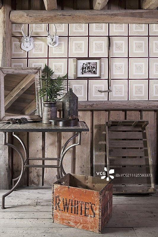 在质朴的阁楼内部，金属框边桌前的旧木箱和格子墙纸图片素材