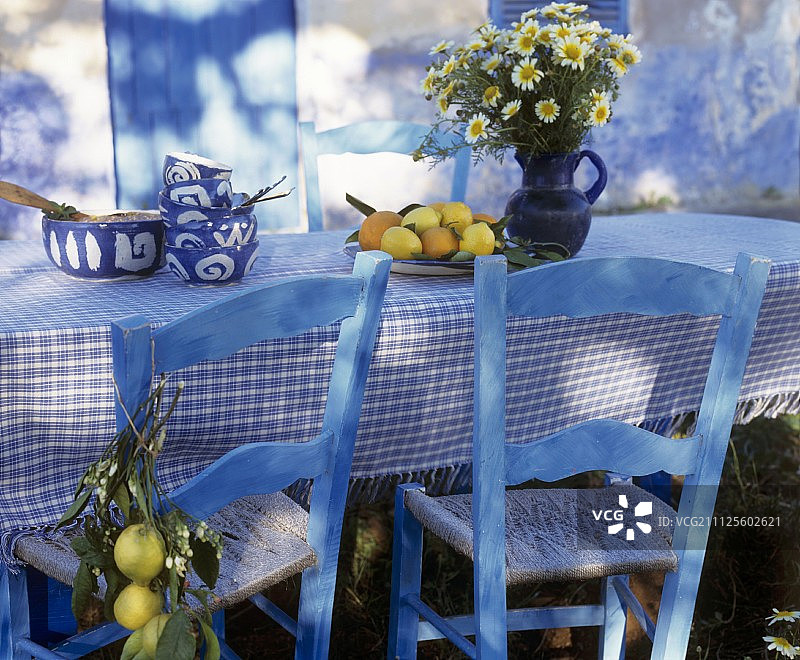 餐桌上的蓝色木椅和地中海风格的白色和蓝色格子布桌布图片素材