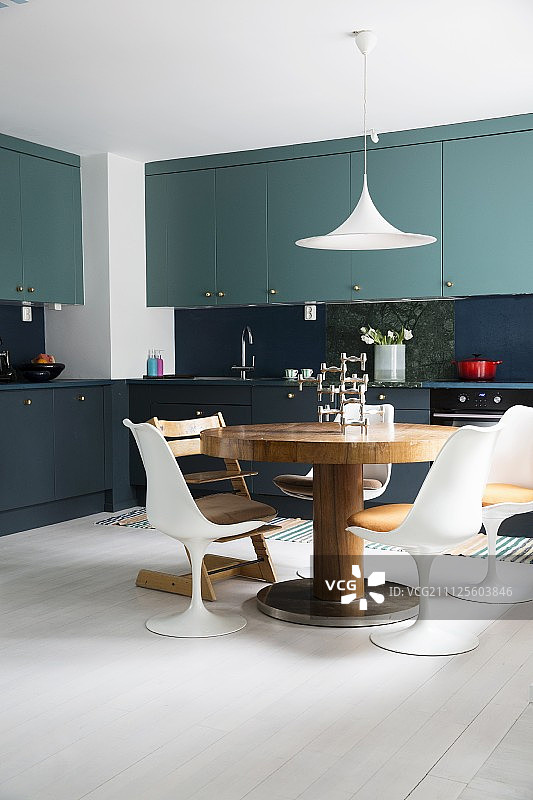 厨房有两种色调的橱柜，圆形餐桌和设计师椅子图片素材