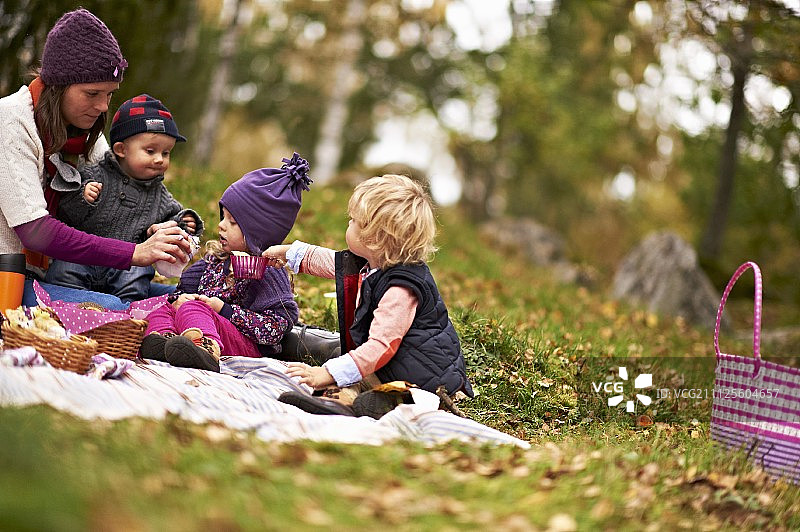 母亲和孩子们享受秋天的森林野餐图片素材