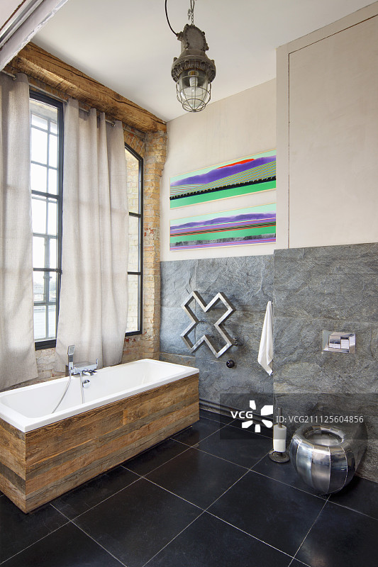 独立的浴缸与乡村木围绕在黑色瓷砖地板阁楼风格的室内图片素材