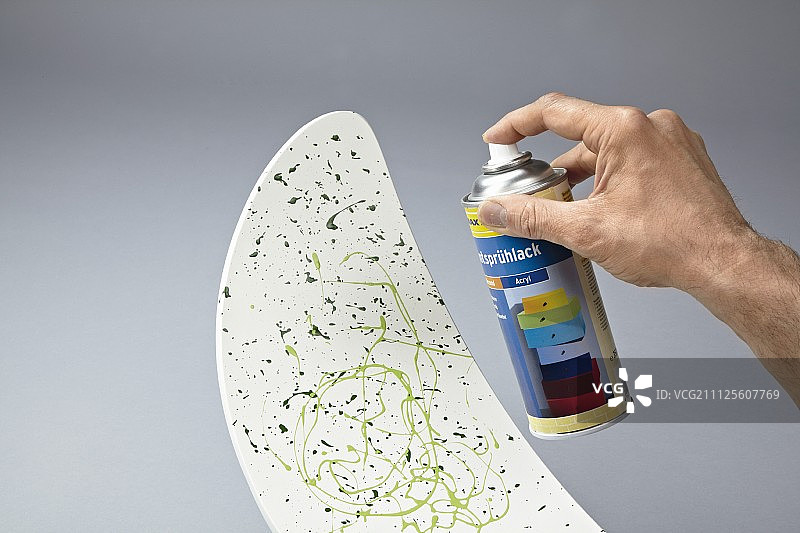 用飞溅的油漆装饰椅子靠背，并用透明喷漆固定图片素材