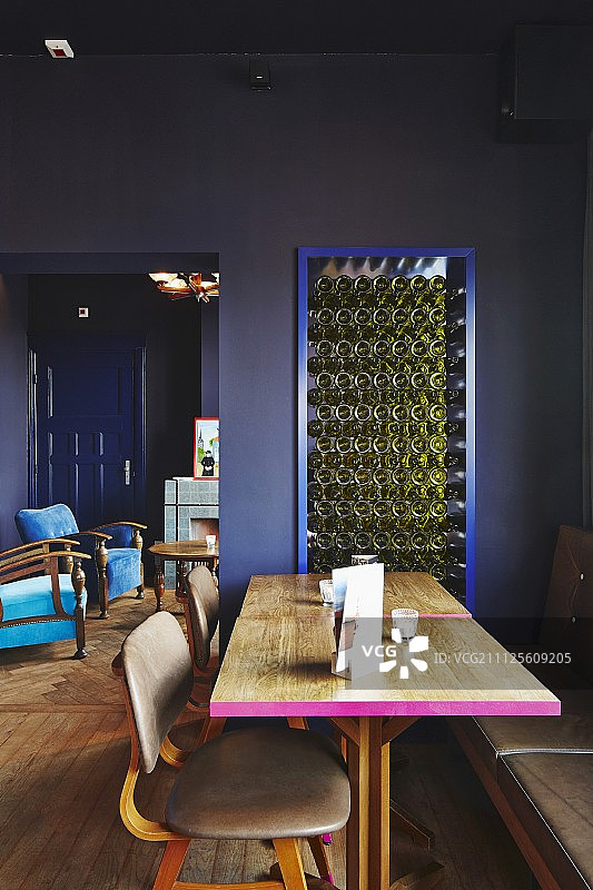 餐厅里的木桌边涂着粉色，椅子上覆盖着皮革，墙壁是深蓝色的图片素材