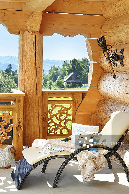 现代户外躺椅，白色坐垫，在小木屋的阳台上可以看到田园诗般的风景图片素材