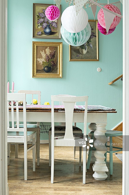 白色的木椅和复古的桌子装饰餐厅与镀金框的花卉图片在蓝色的墙壁上图片素材