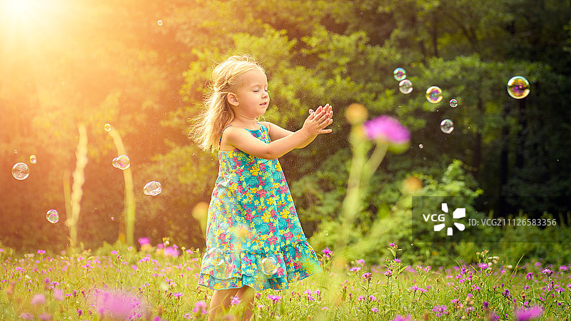 可爱的小金发女孩玩肥皂泡在阳光明媚的夏天下午图片素材