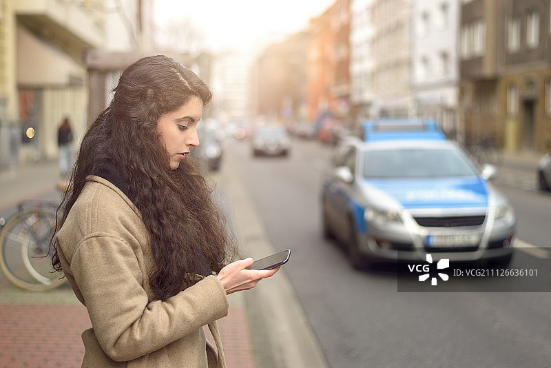 黑发女子在繁忙的街道边发短信图片素材