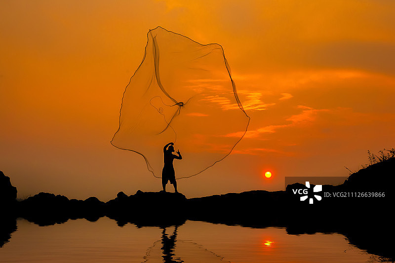 渔夫在夕阳下垂钓。图片素材
